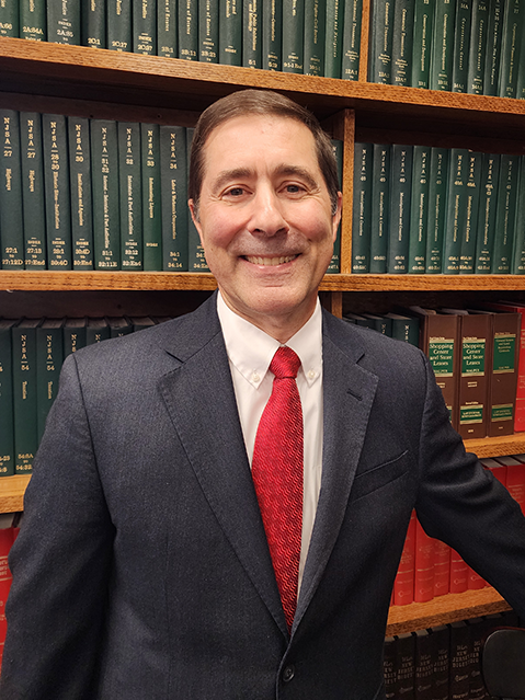 photograph of a man in a suit with law books behind him